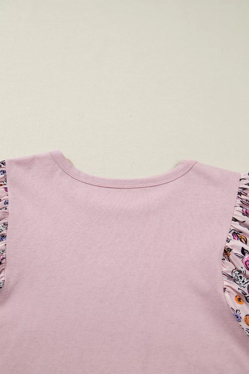 Light pink tee with floral puff sleeves and an oversized floral appliqué on the front styled with denim shorts.