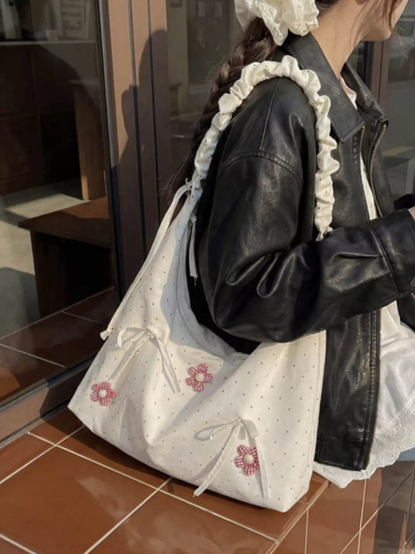 Medium shoulder bag with daisy floral appliqués, bow details, dotted fabric, ruffled strap, and soft cottagecore styling.