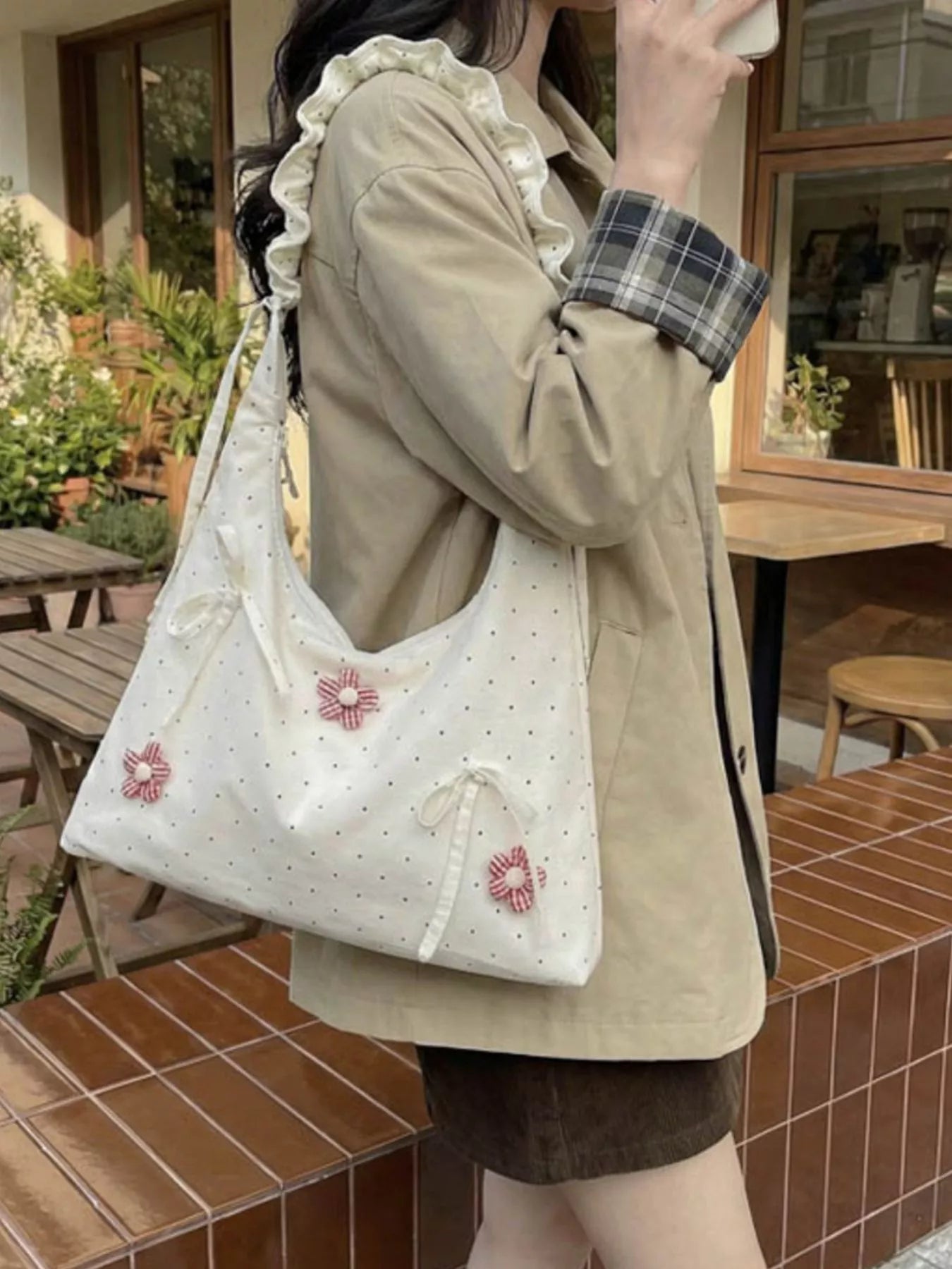 Medium shoulder bag with daisy floral appliqués, bow details, dotted fabric, ruffled strap, and soft cottagecore styling.