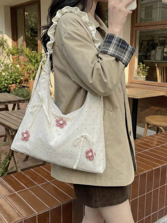 Medium shoulder bag with daisy floral appliqués, bow details, dotted fabric, ruffled strap, and soft cottagecore styling.