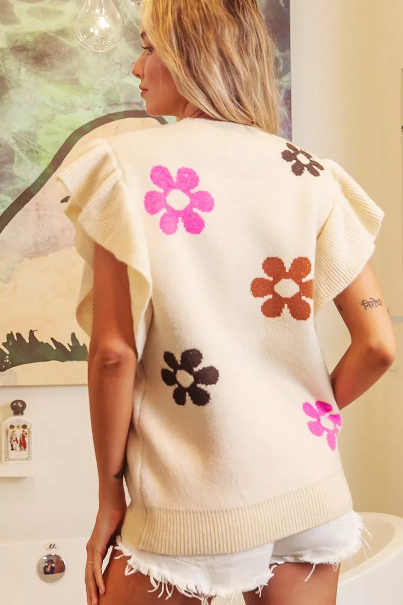 Cream floral ruffle sleeve knit top with colorful daisy details, waffle-knit texture, ribbed trim, and oversized fit.