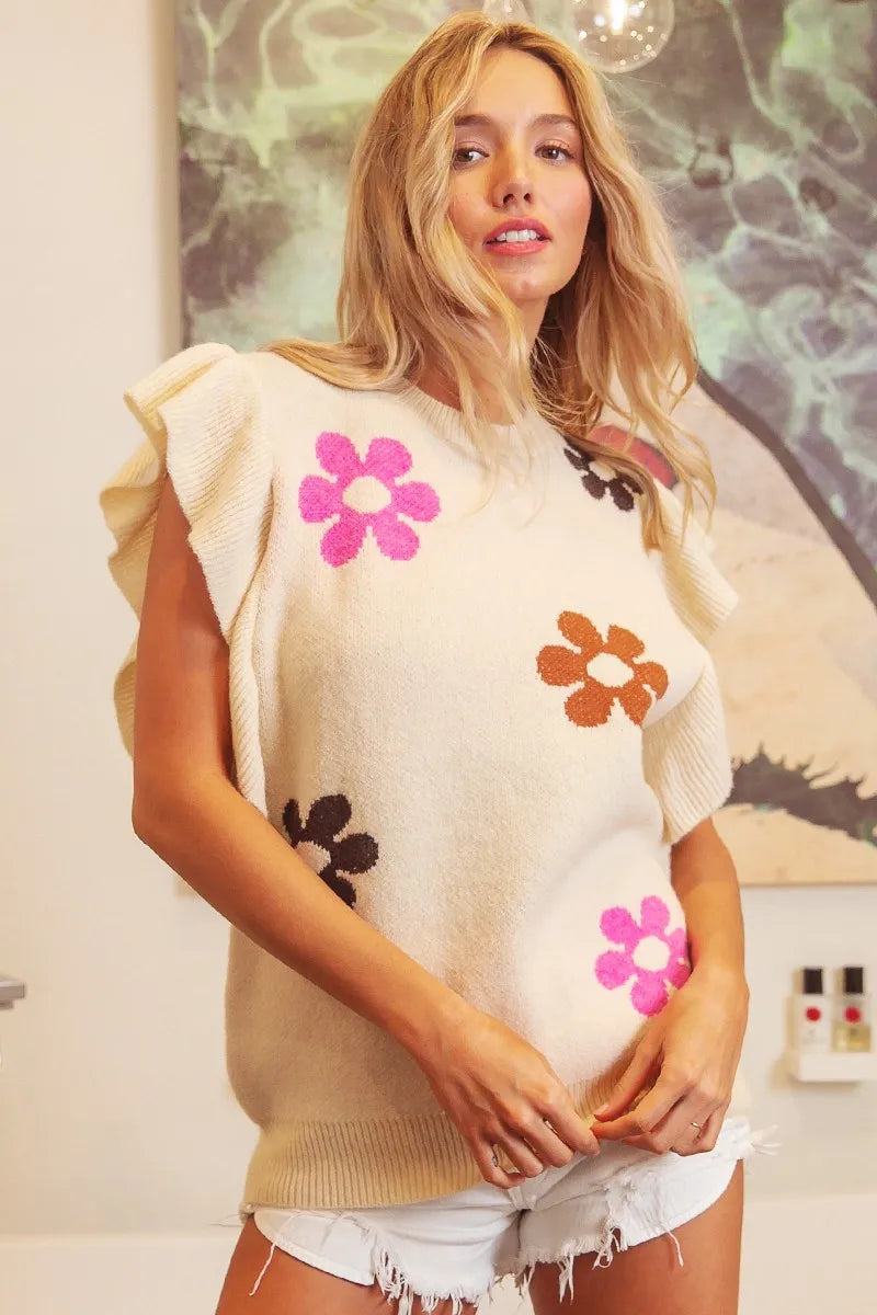 Cream floral ruffle sleeve knit top with colorful daisy details, waffle-knit texture, ribbed trim, and oversized fit.