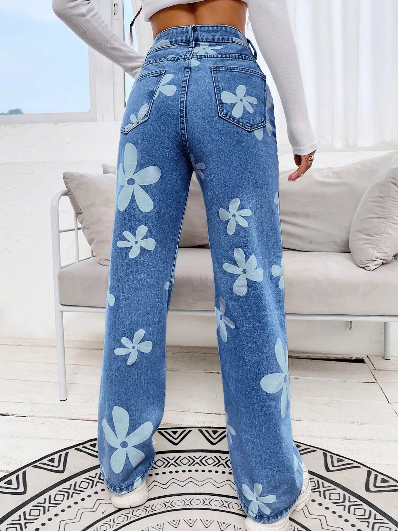 Wide-leg jeans with oversized daisy print, pocketed design, high-rise fit, and relaxed statement denim style.