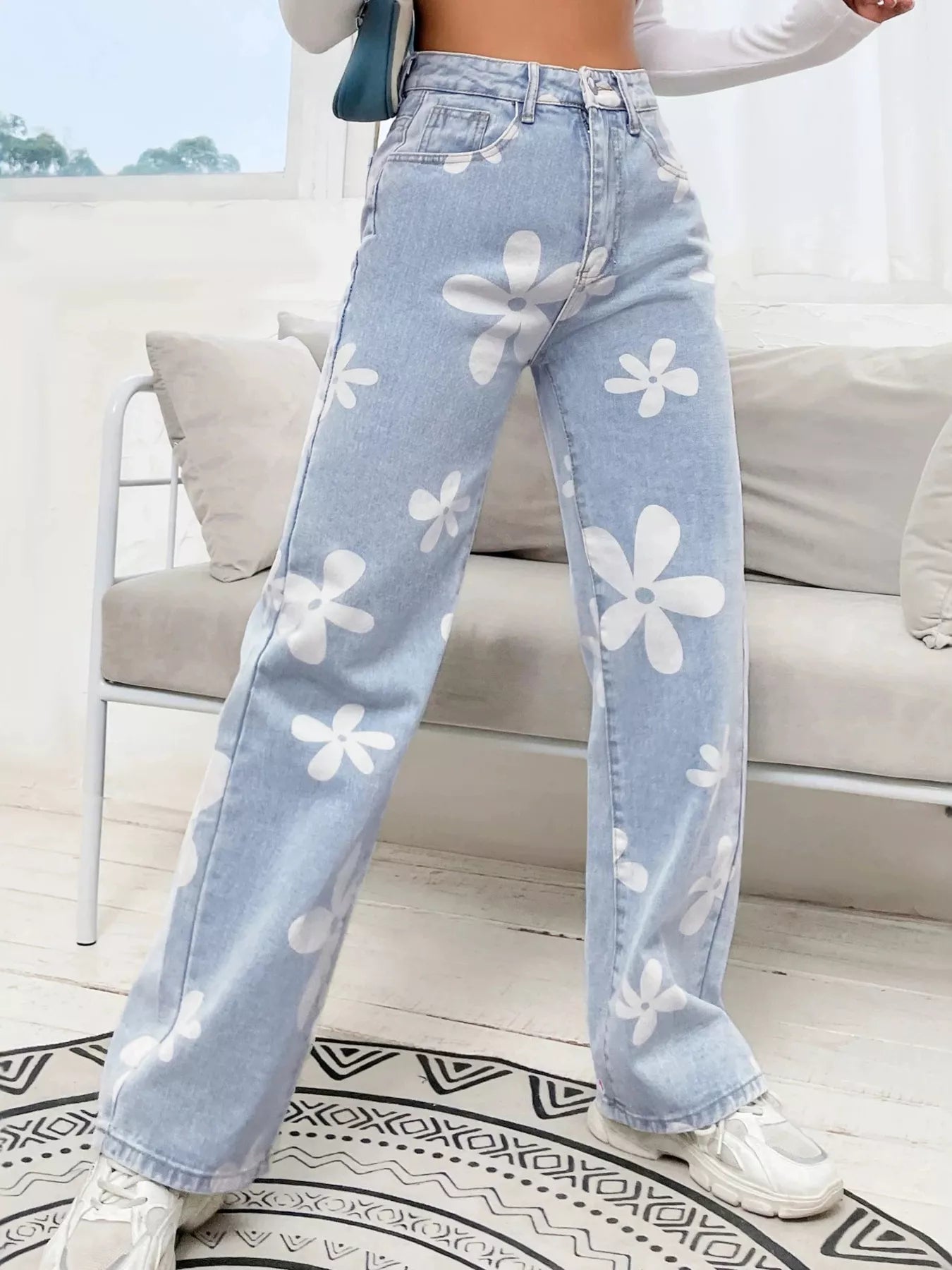 Wide-leg jeans with oversized daisy print, pocketed design, high-rise fit, and relaxed statement denim style.