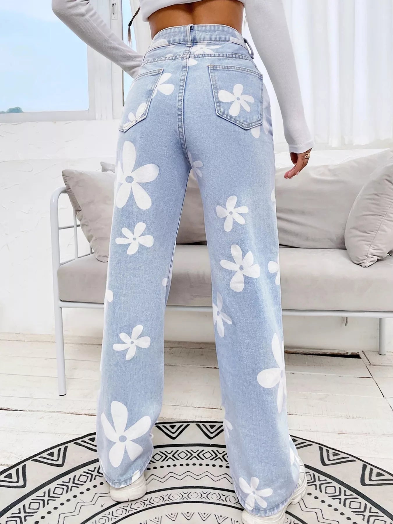 Wide-leg jeans with oversized daisy print, pocketed design, high-rise fit, and relaxed statement denim style.
