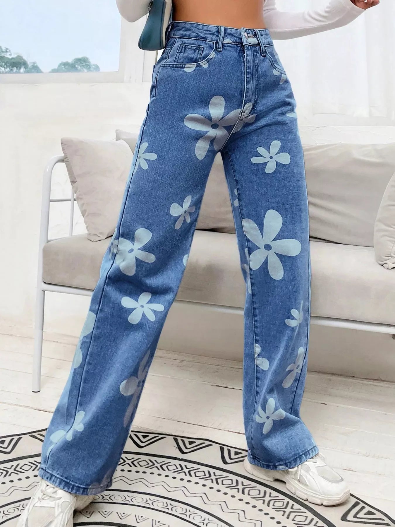 Wide-leg jeans with oversized daisy print, pocketed design, high-rise fit, and relaxed statement denim style.