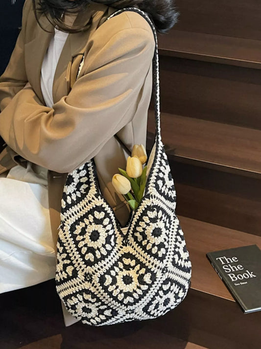 Black and cream crochet shoulder bag with a floral square pattern and roomy large silhouette worn over the shoulder.