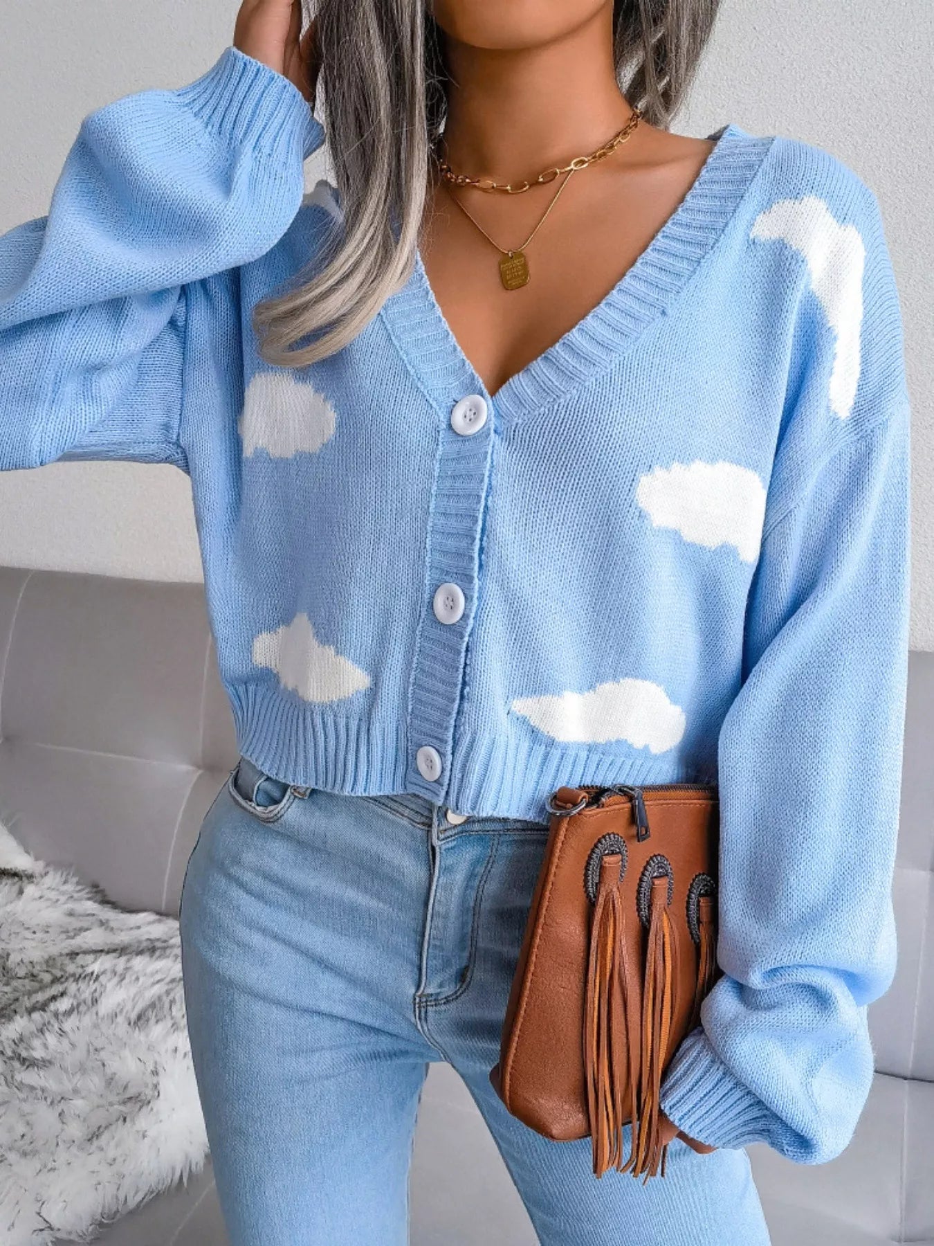 Woman wearing a pastel cloud-patterned knit cardigan with buttons — whimsical cropped sweater from A Whimsical Affair.