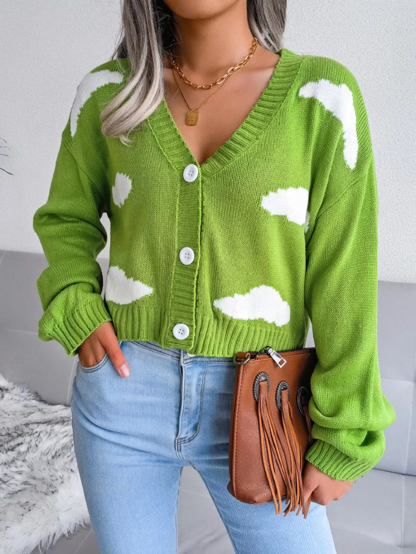 Woman wearing a pastel cloud-patterned knit cardigan with buttons — whimsical cropped sweater from A Whimsical Affair.