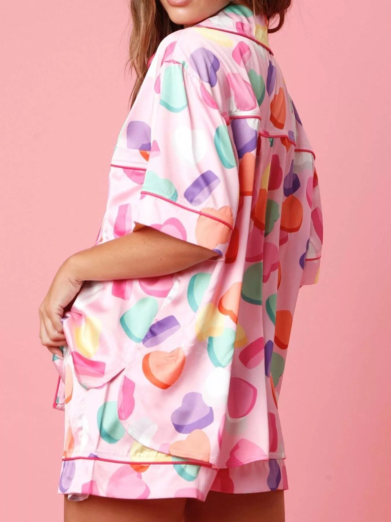 Women’s short sleeve button-up pajama set with colorful candy heart print on pink background