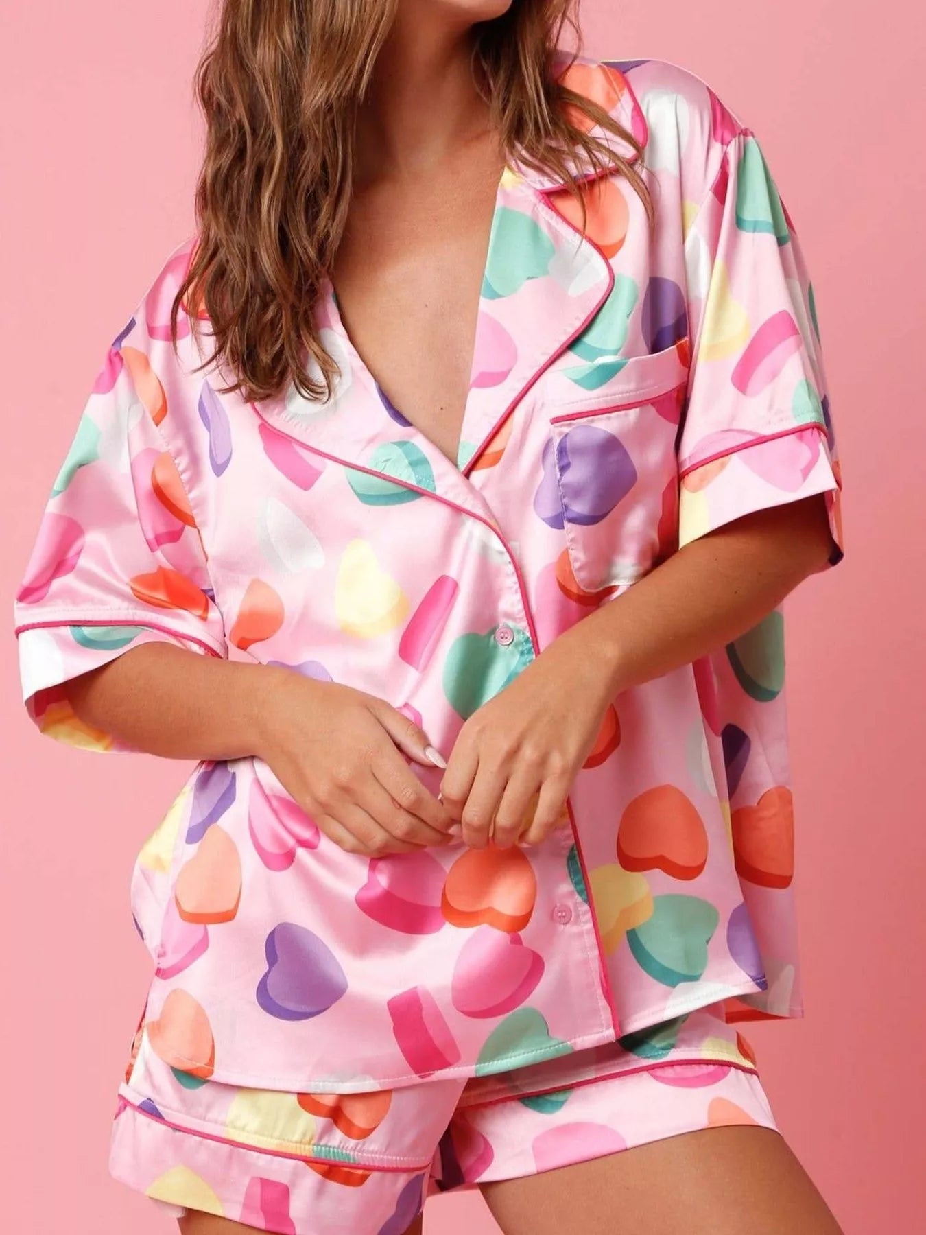 Women’s short sleeve button-up pajama set with colorful candy heart print on pink background