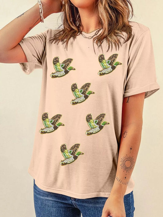Woman wearing tan Duckie Sparkle Tee with sequin duck designs, fun quirky casual top for animal lovers.
