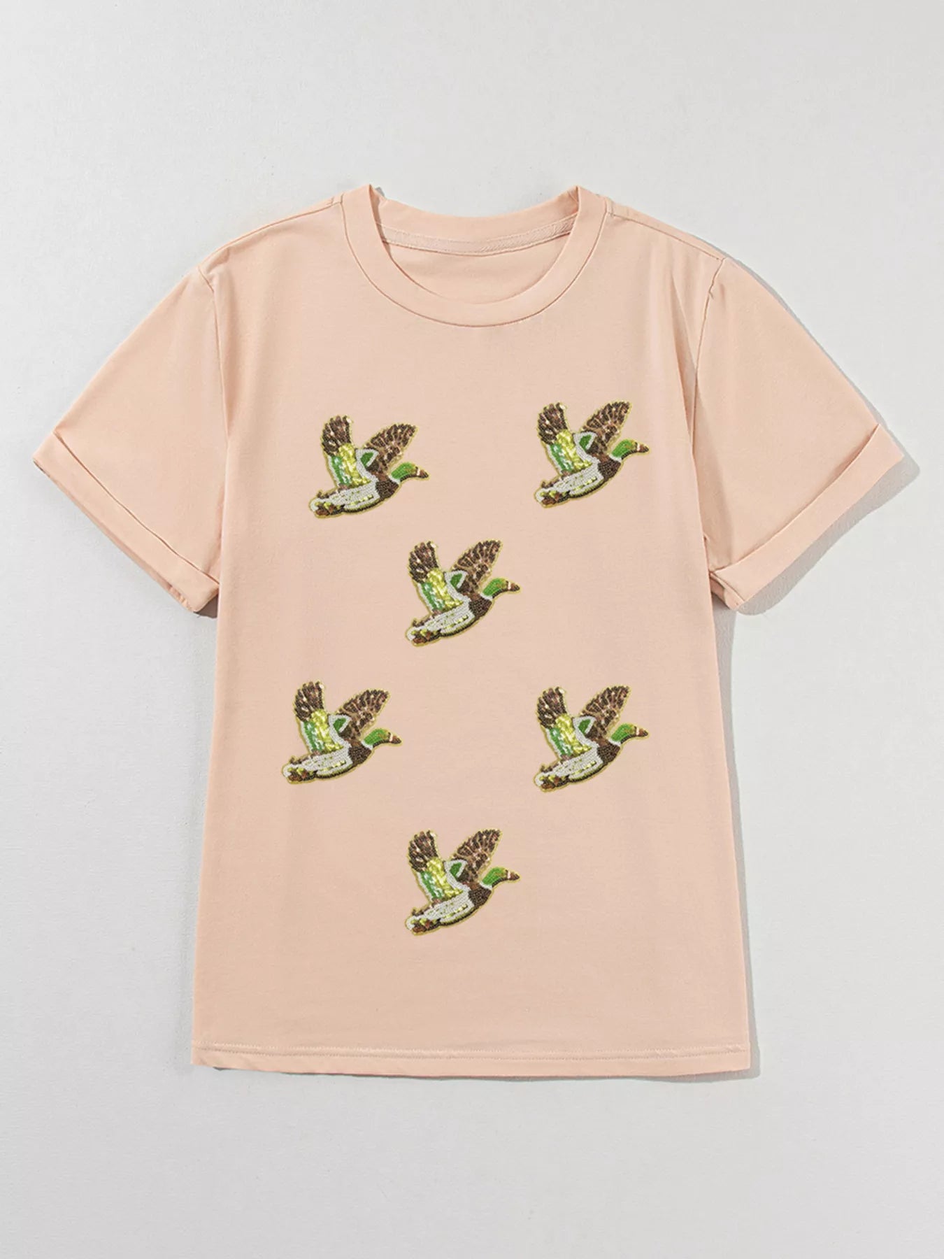 Woman wearing tan Duckie Sparkle Tee with sequin duck designs, fun quirky casual top for animal lovers.