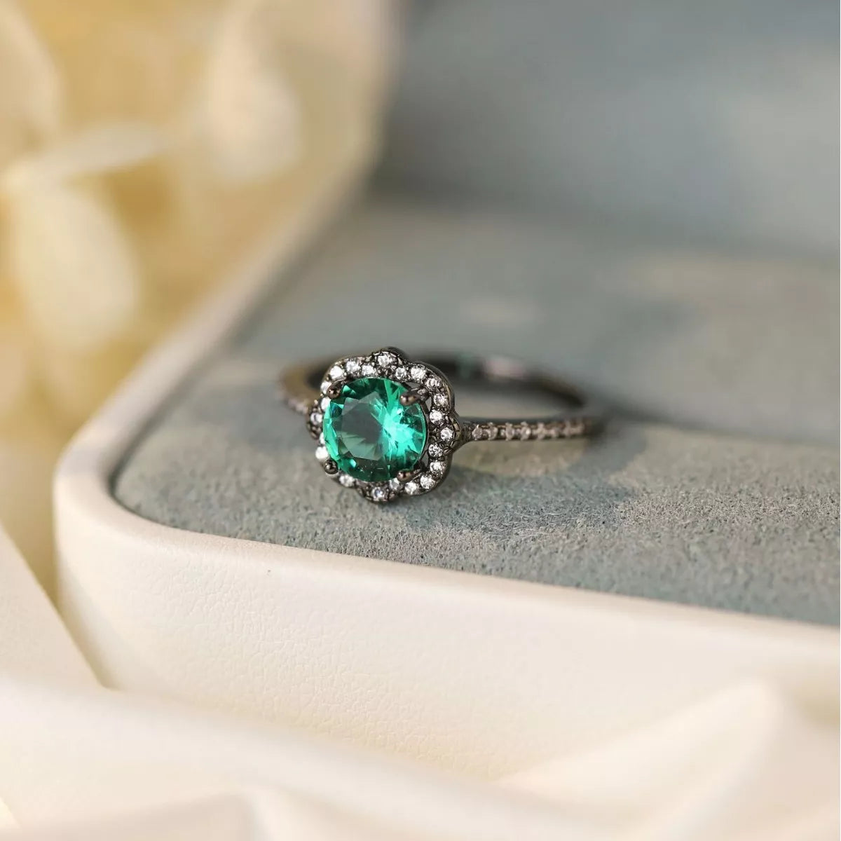 Sterling silver ring with teal center stone and zircon floral halo detailing.