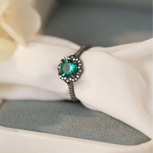 Sterling silver ring with teal center stone and zircon floral halo detailing.