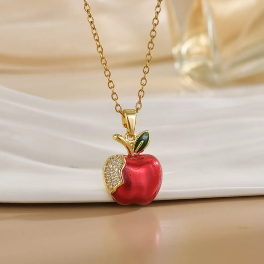 Gold apple necklace with red enamel charm and crystal detail on chain