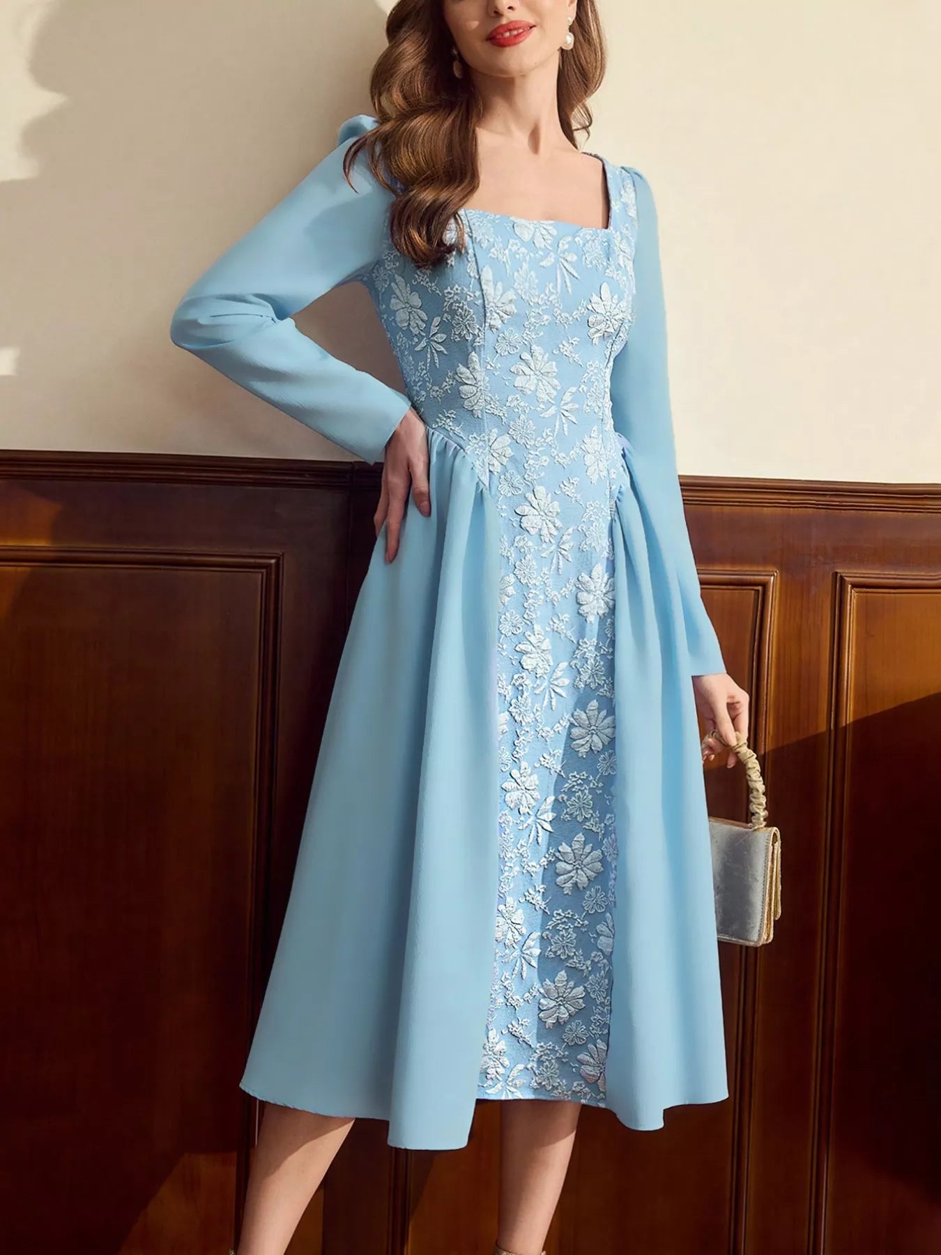 Woman wearing a light blue midi dress with long sleeves, square neckline, and white floral embroidery on the front panel.