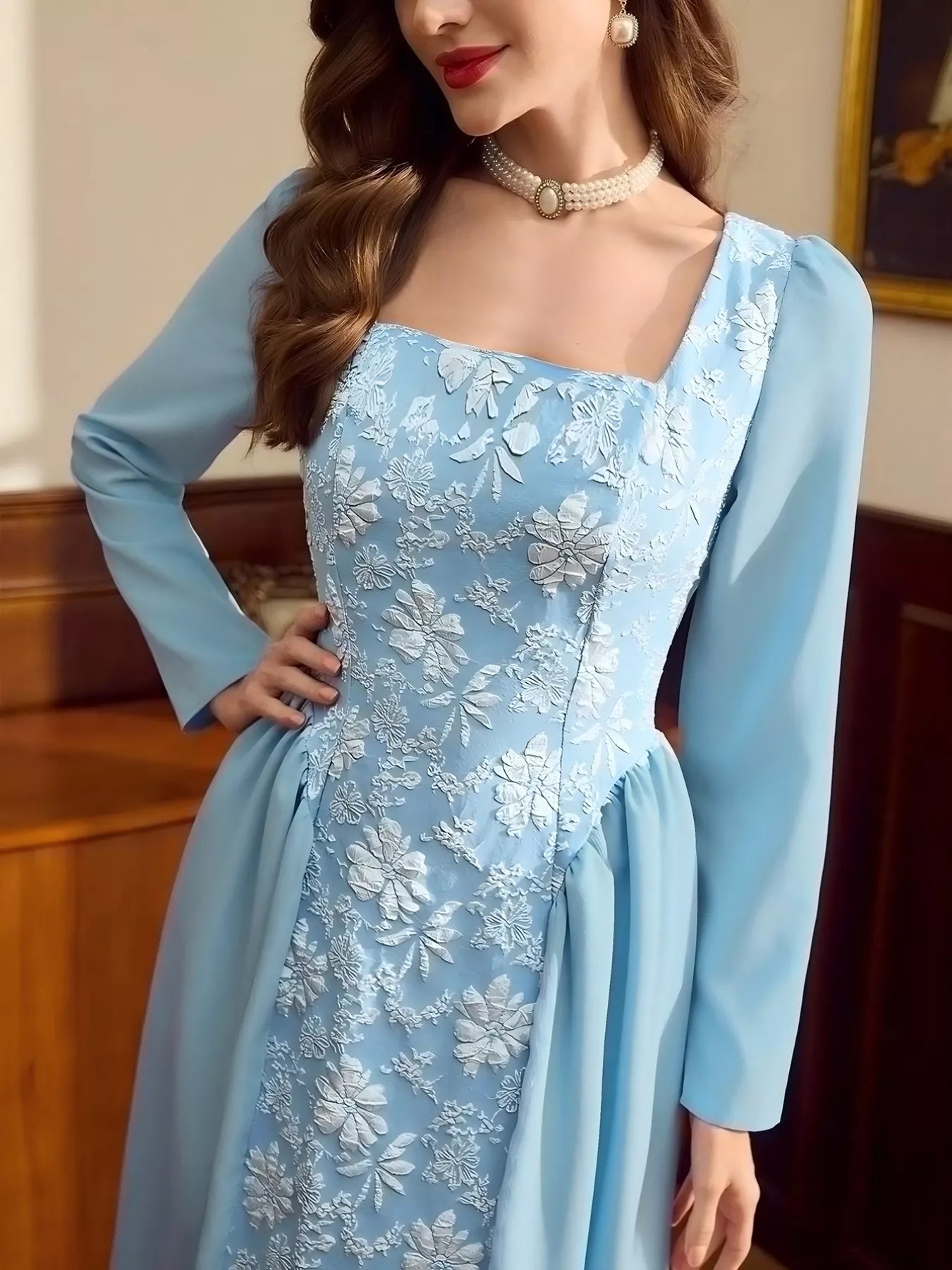 Woman wearing a light blue midi dress with long sleeves, square neckline, and white floral embroidery on the front panel.