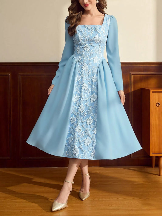 Woman wearing a light blue midi dress with long sleeves, square neckline, and white floral embroidery on the front panel.