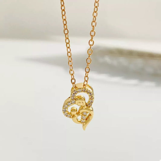 Close-up of woman wearing a gold-plated heart-shaped zircon necklace on a delicate chain, styled with a brown ribbed top for an elegant look.