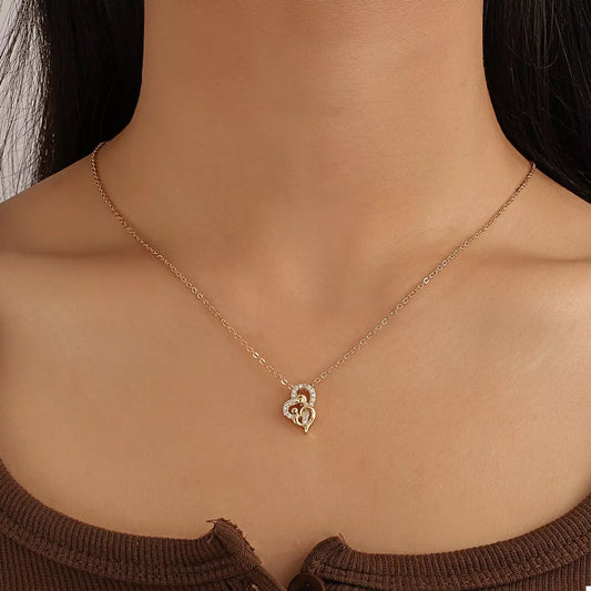 Close-up of woman wearing a gold-plated heart-shaped zircon necklace on a delicate chain, styled with a brown ribbed top for an elegant look.
