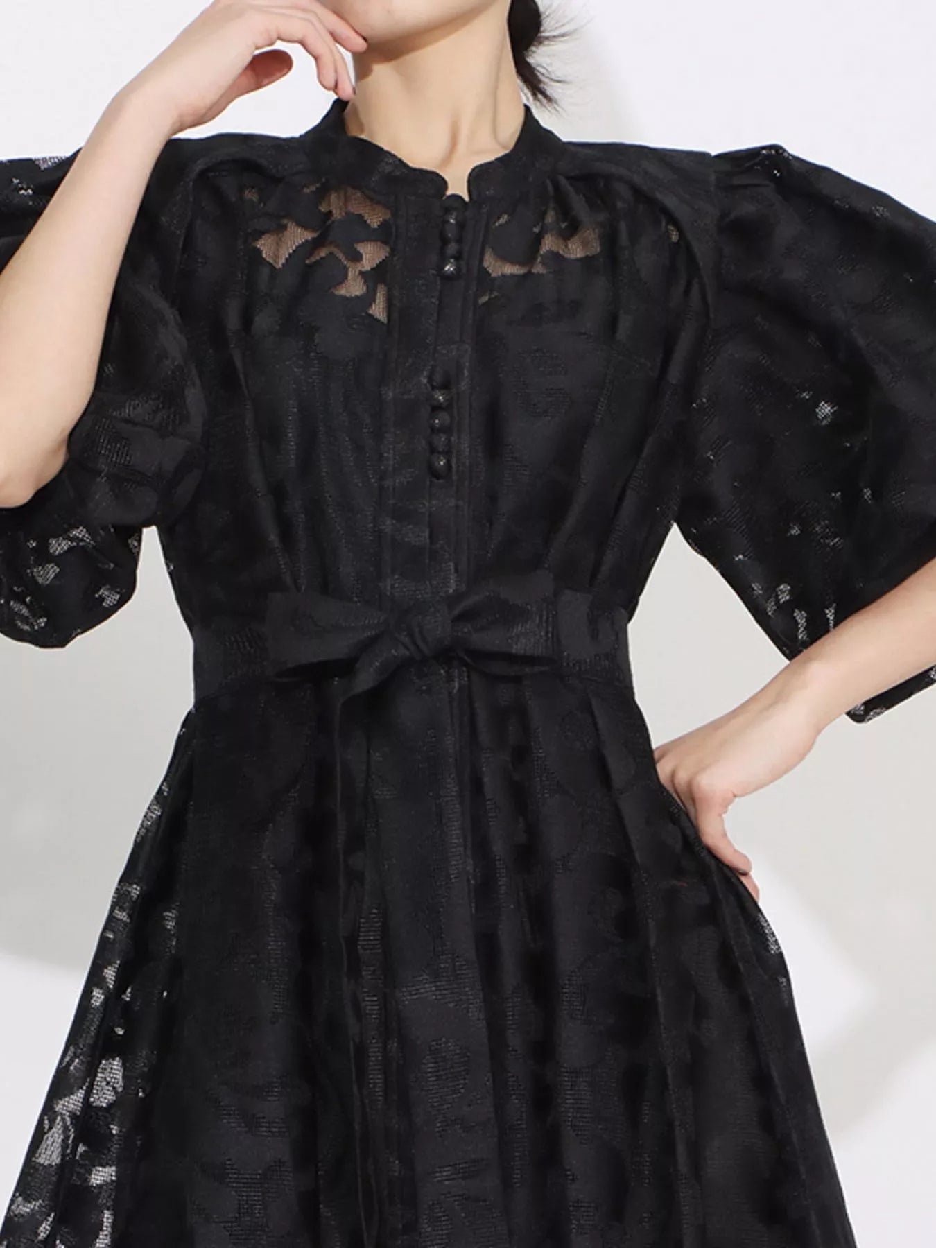 Model wearing the Ethereal Grace Lace Maxi Dress in black, with puff sleeves, button-down front, tie waist, and sheer lace fabric for an elegant look.
