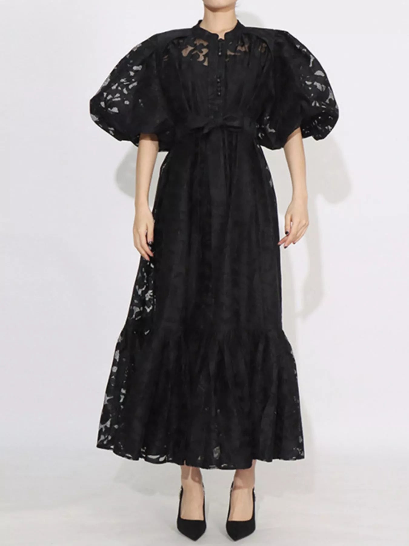 Model wearing the Ethereal Grace Lace Maxi Dress in black, with puff sleeves, button-down front, tie waist, and sheer lace fabric for an elegant look.