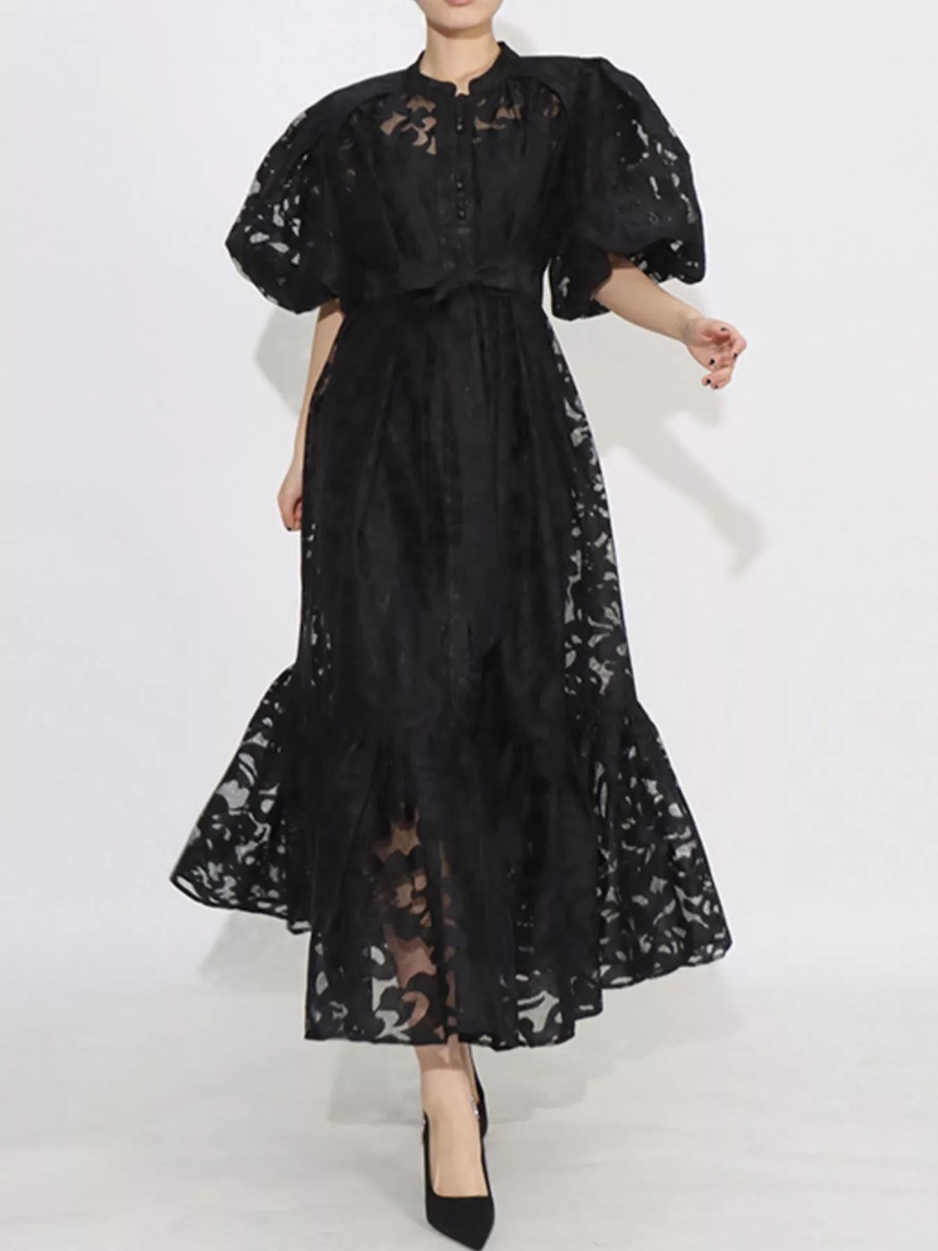 Model wearing the Ethereal Grace Lace Maxi Dress in black, with puff sleeves, button-down front, tie waist, and sheer lace fabric for an elegant look.