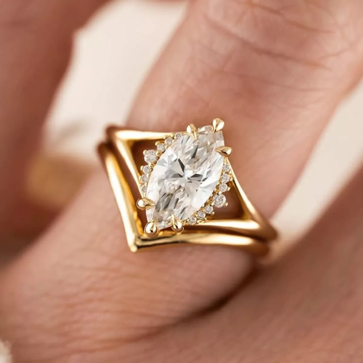 Gold two-piece marquise-cut moissanite ring set with a heart-shaped curved band displayed in a blush jewelry box.