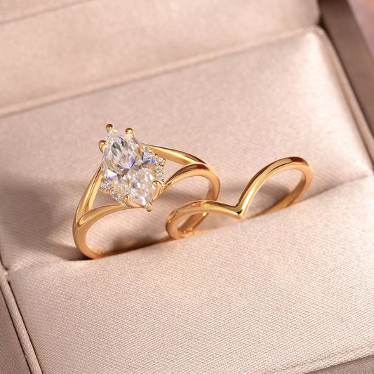 Gold two-piece marquise-cut moissanite ring set with a heart-shaped curved band displayed in a blush jewelry box.