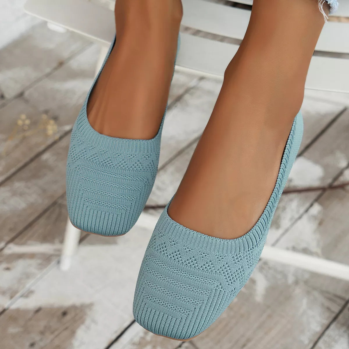 Close-up of sky blue knit square toe slip-on flats with low heel on wooden floor.