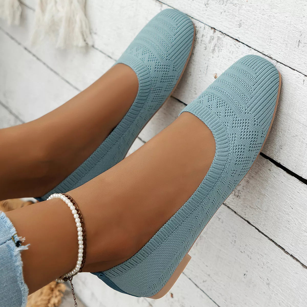 Close-up of sky blue knit square toe slip-on flats with low heel on wooden floor.