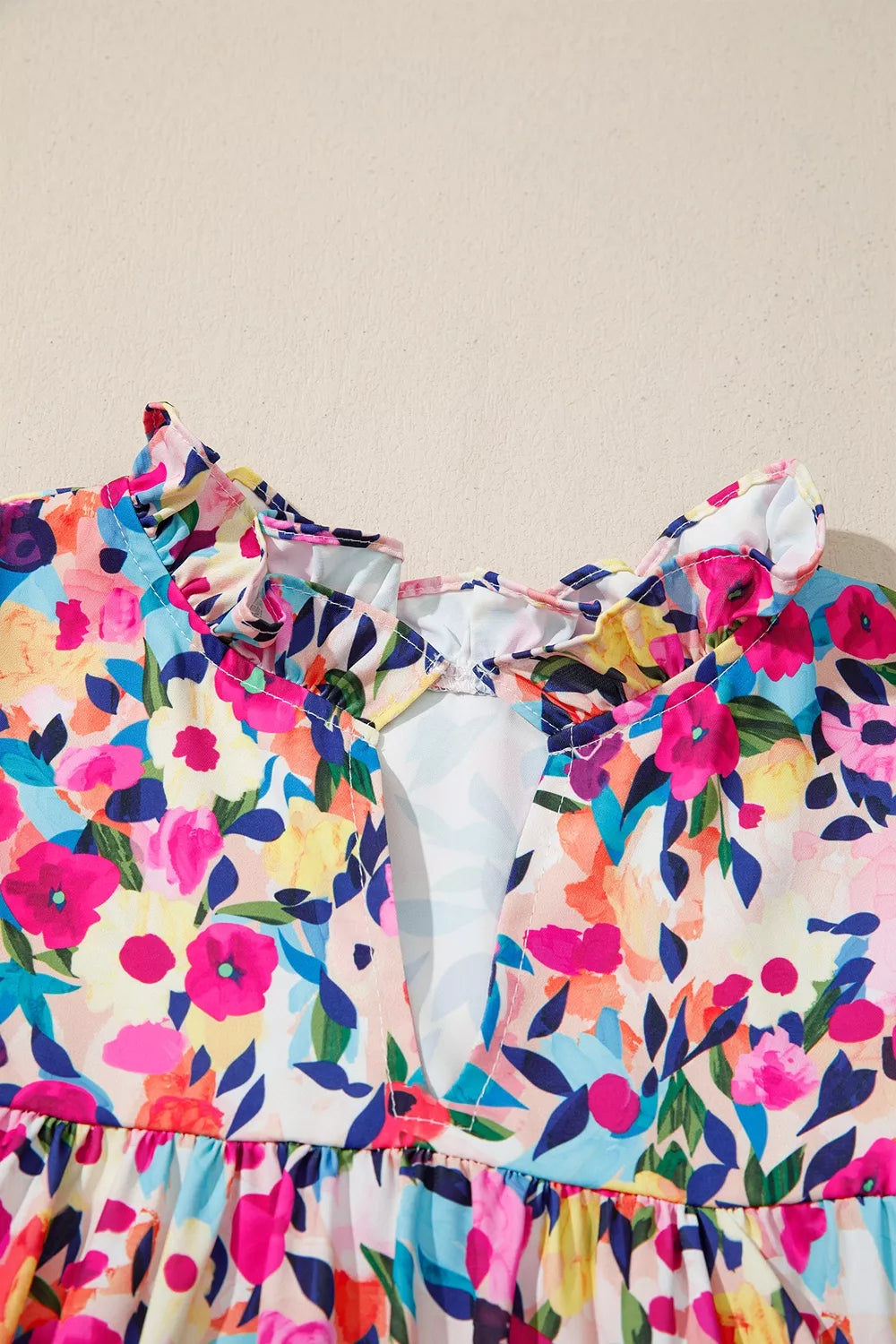 Colorful floral blouse with frill neckline detail, puff-style short sleeves, relaxed fit, and slightly stretchy fabric styled with denim shorts.