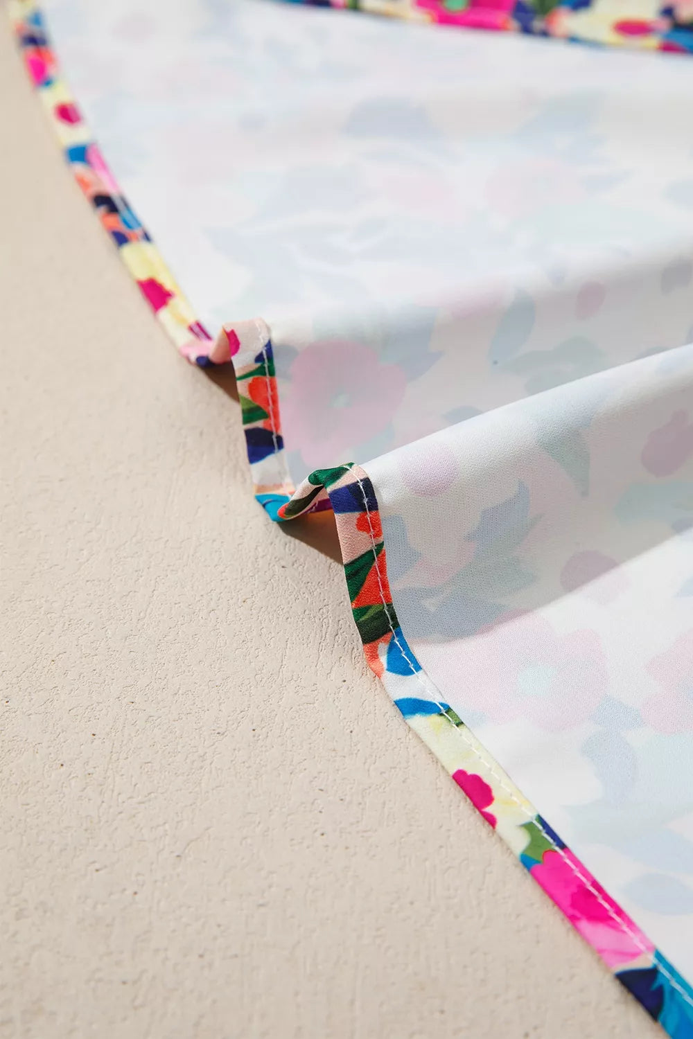 Colorful floral blouse with frill neckline detail, puff-style short sleeves, relaxed fit, and slightly stretchy fabric styled with denim shorts.