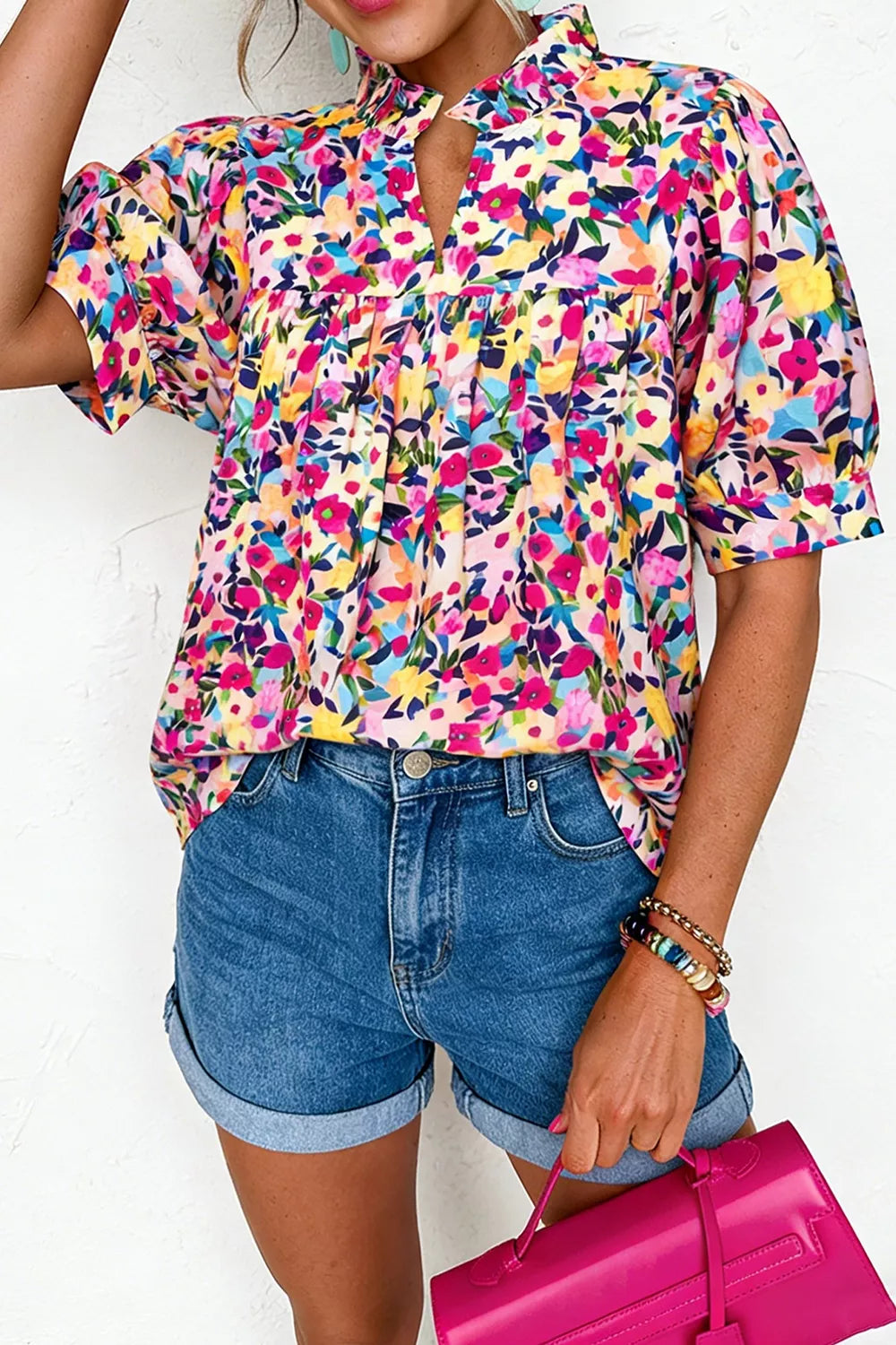 Colorful floral blouse with frill neckline detail, puff-style short sleeves, relaxed fit, and slightly stretchy fabric styled with denim shorts.