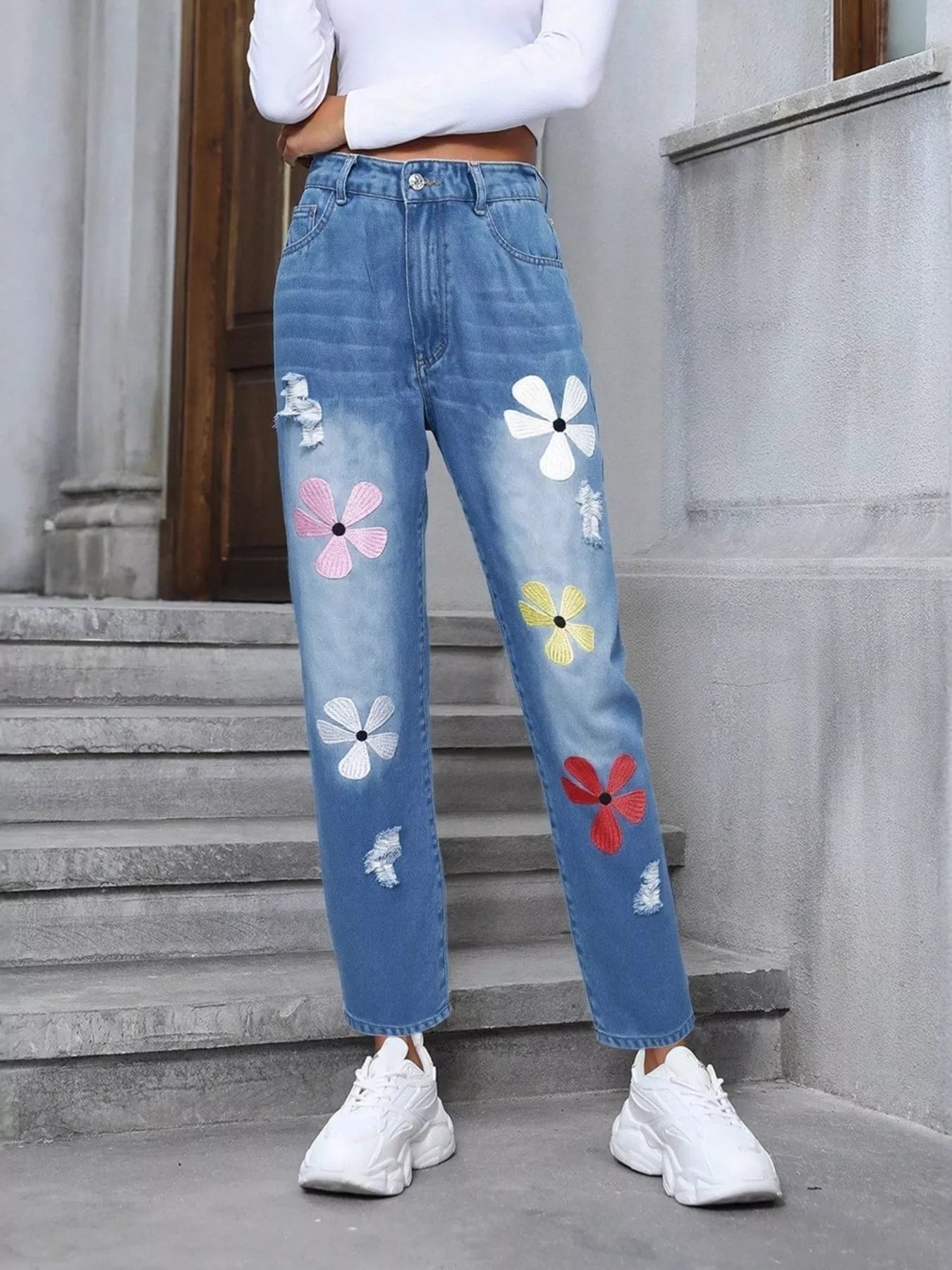 Light blue distressed high-waist jeans with colorful embroidered floral appliqué patches.
