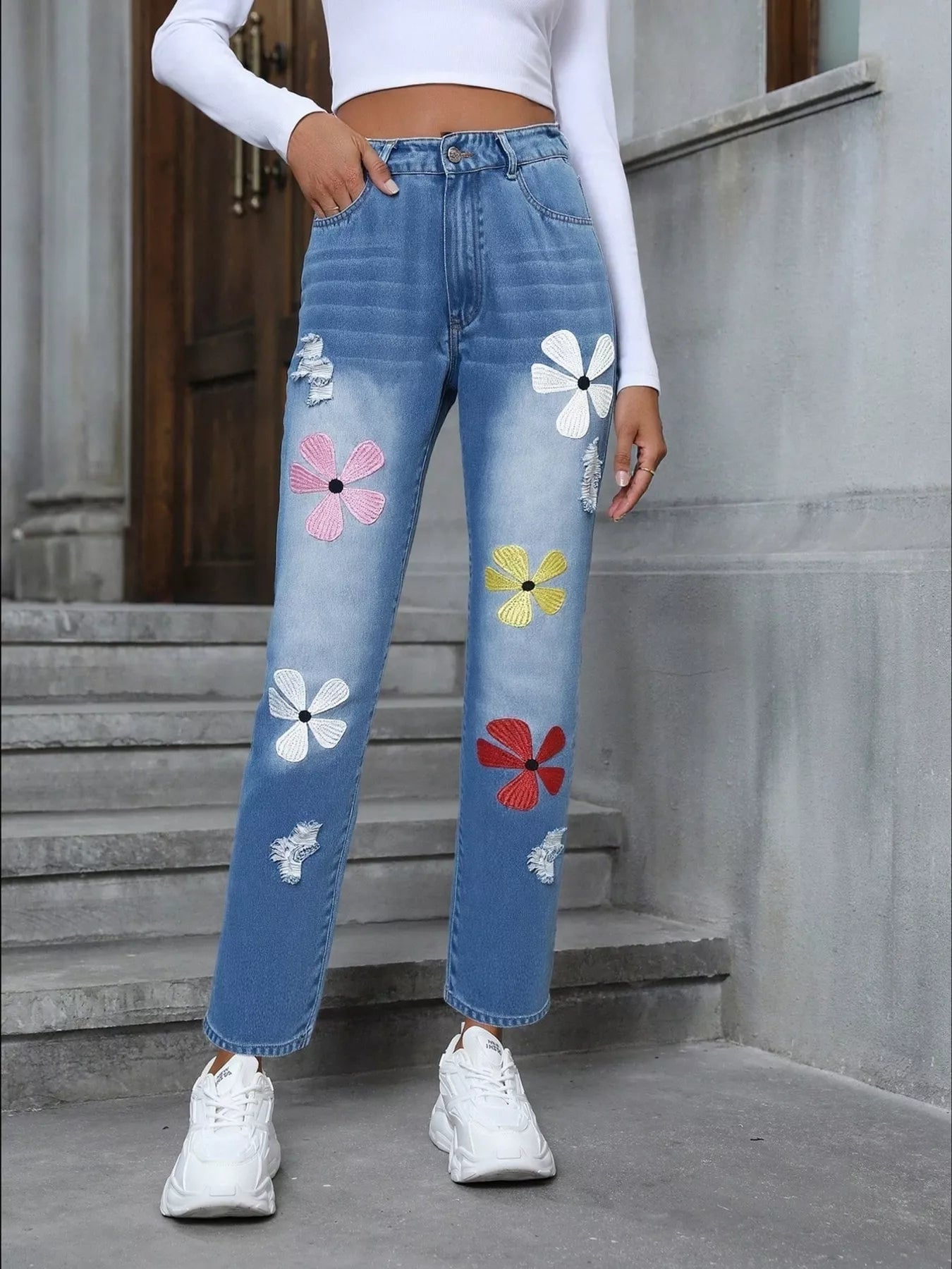 Light blue distressed high-waist jeans with colorful embroidered floral appliqué patches.