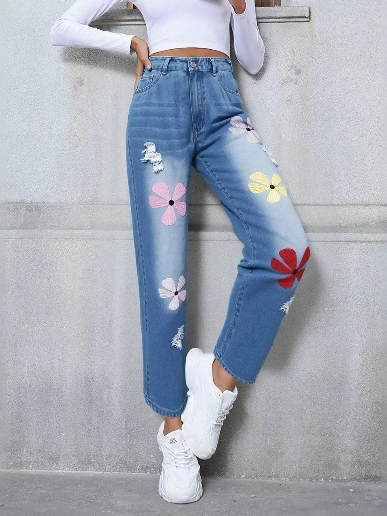 Light blue distressed high-waist jeans with colorful embroidered floral appliqué patches.