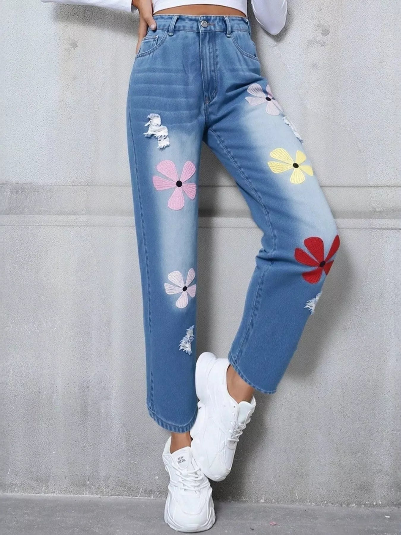 Light blue distressed high-waist jeans with colorful embroidered floral appliqué patches.