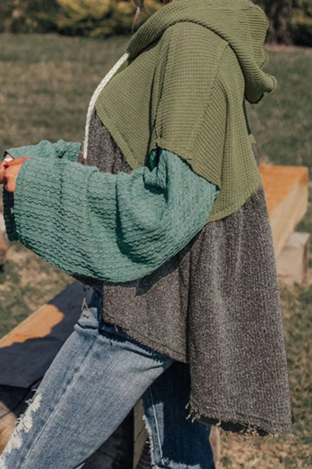 Woman wearing a colorblock drawstring hoodie with distressed jeans outdoors