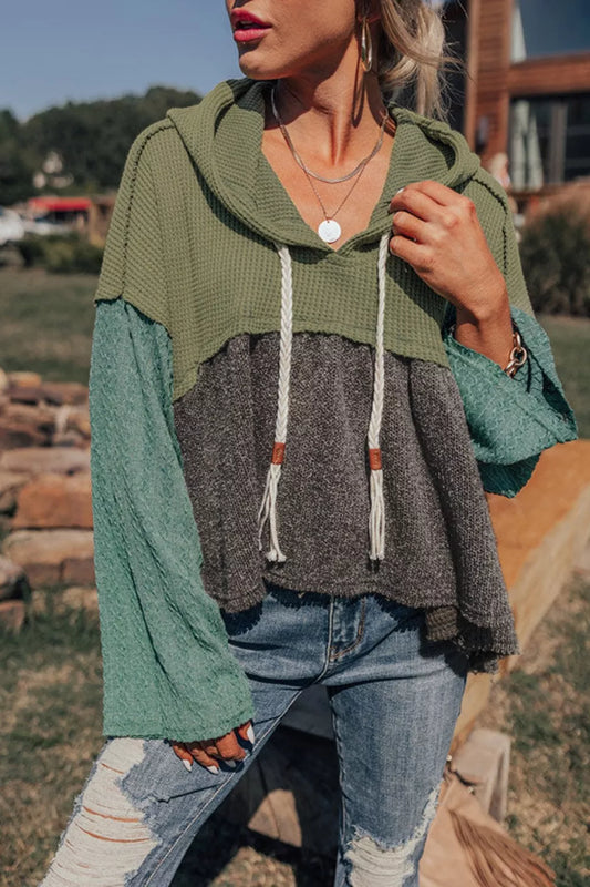 Woman wearing a colorblock drawstring hoodie with distressed jeans outdoors