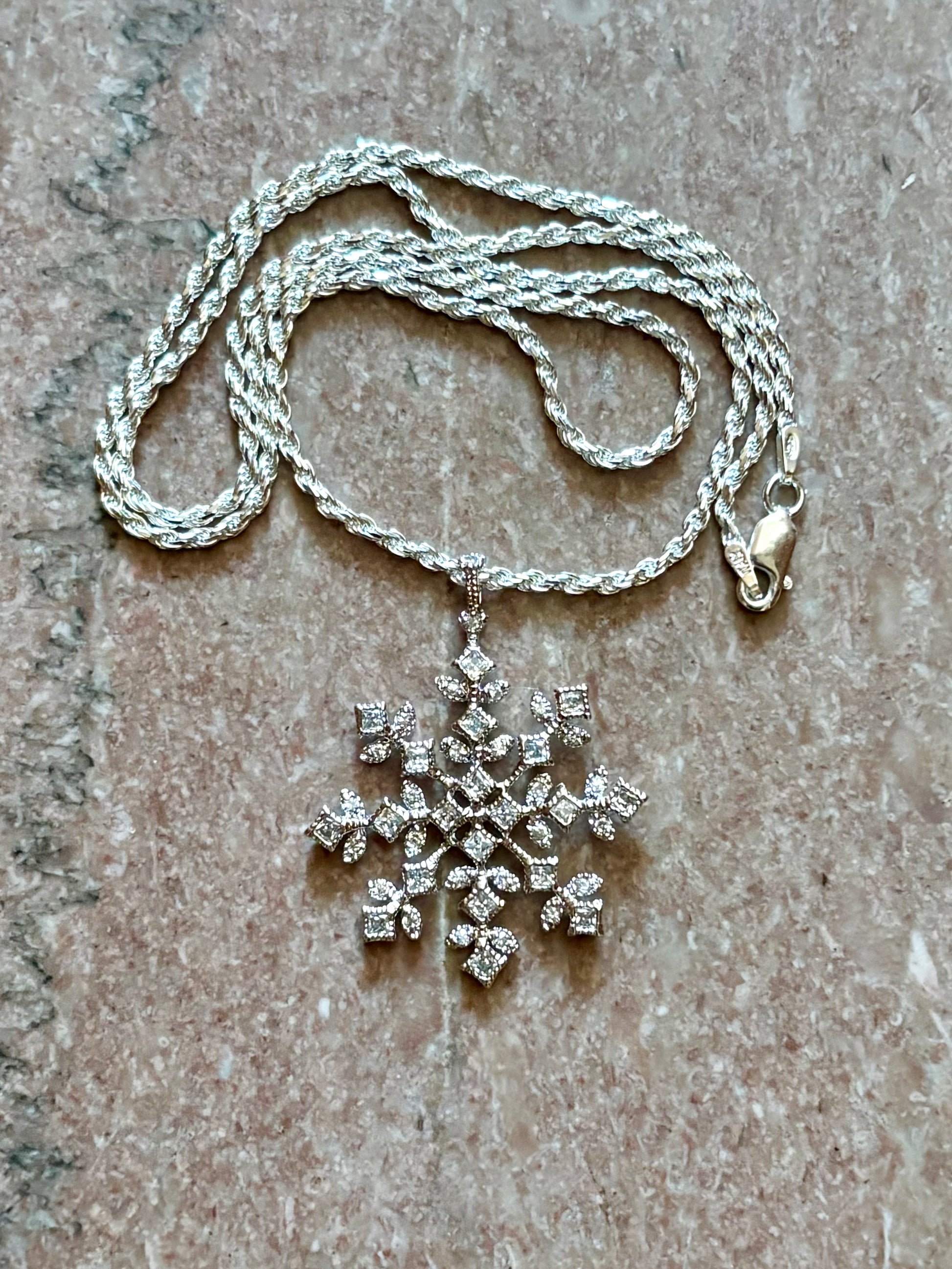 Sterling silver snowflake pendant necklace from the Enchanted Crystals Collection, worn on a matching silver chain.