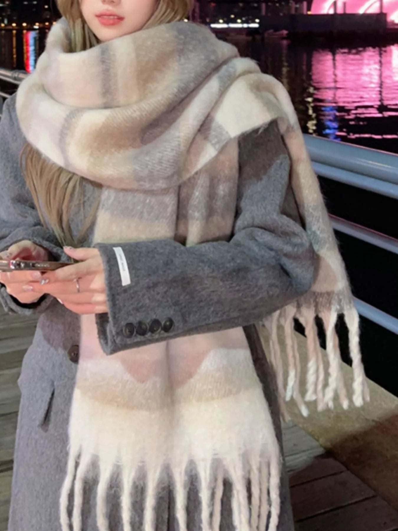 Oversized soft fringe scarf in pastel gradient tones, worn layered as a winter wrap.