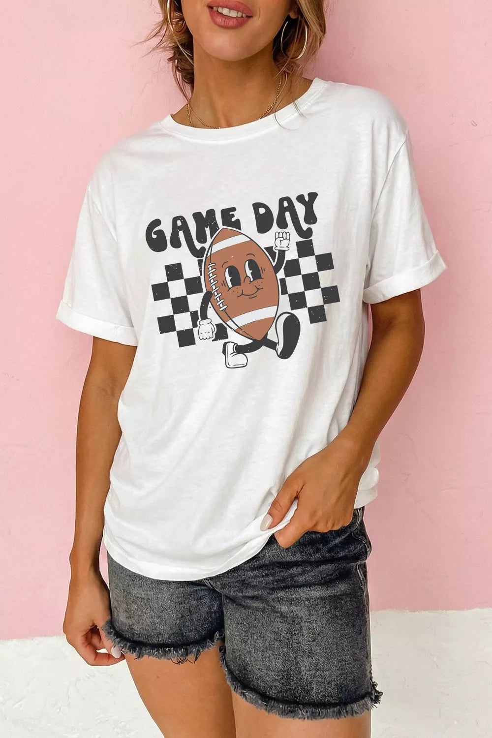 White graphic tee with bold “Game Day” text, a smiling football illustration, and black checkerboard accents.