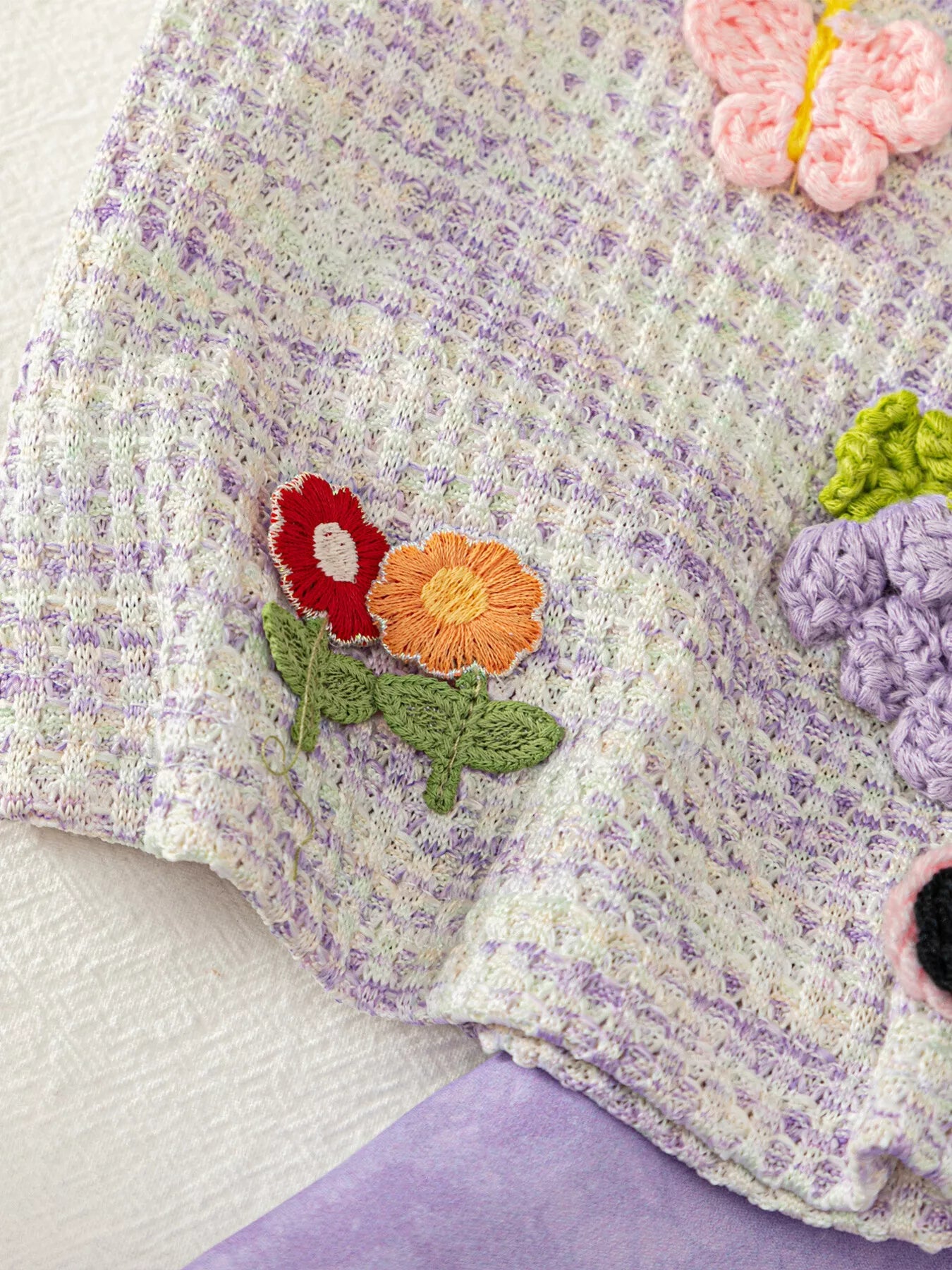 Two-piece baby outfit with textured appliqué sleeveless top, daisy trim neckline, and lavender flowy shorts.