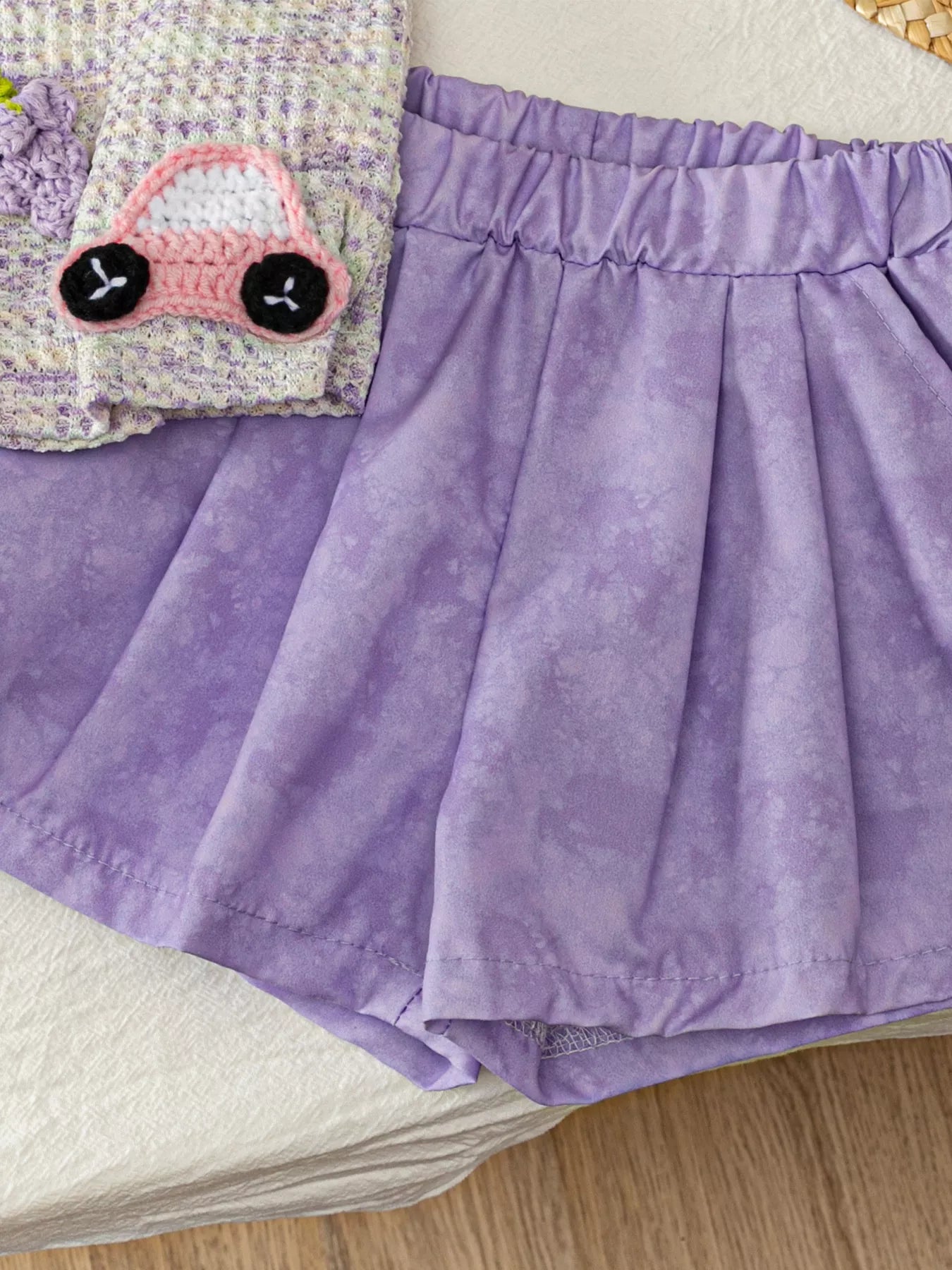 Two-piece baby outfit with textured appliqué sleeveless top, daisy trim neckline, and lavender flowy shorts.