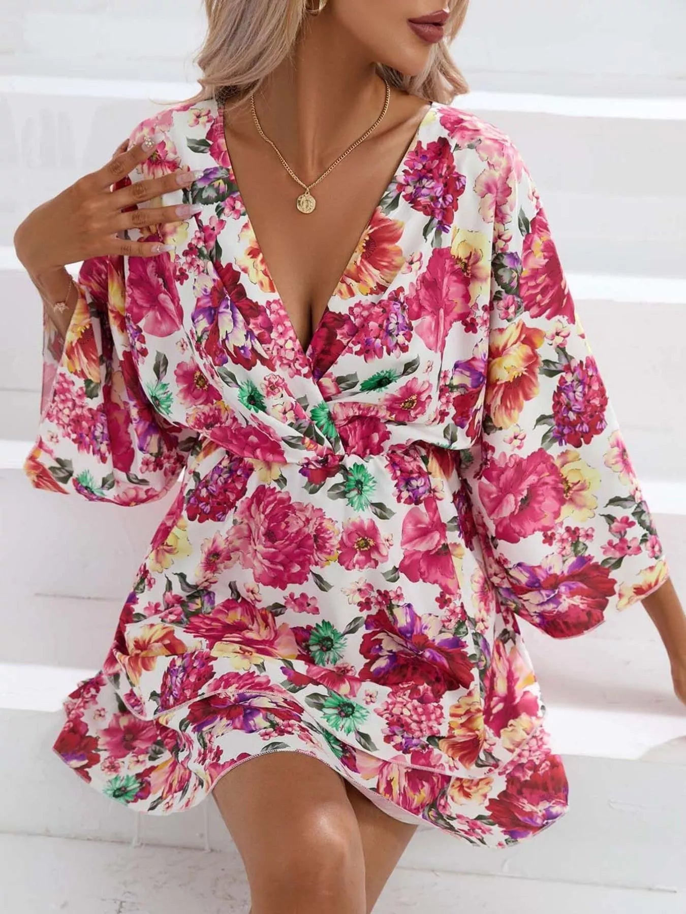 Floral mini dress with a surplice V-neckline, flowy sleeves, tiered skirt, and bright pink floral print.