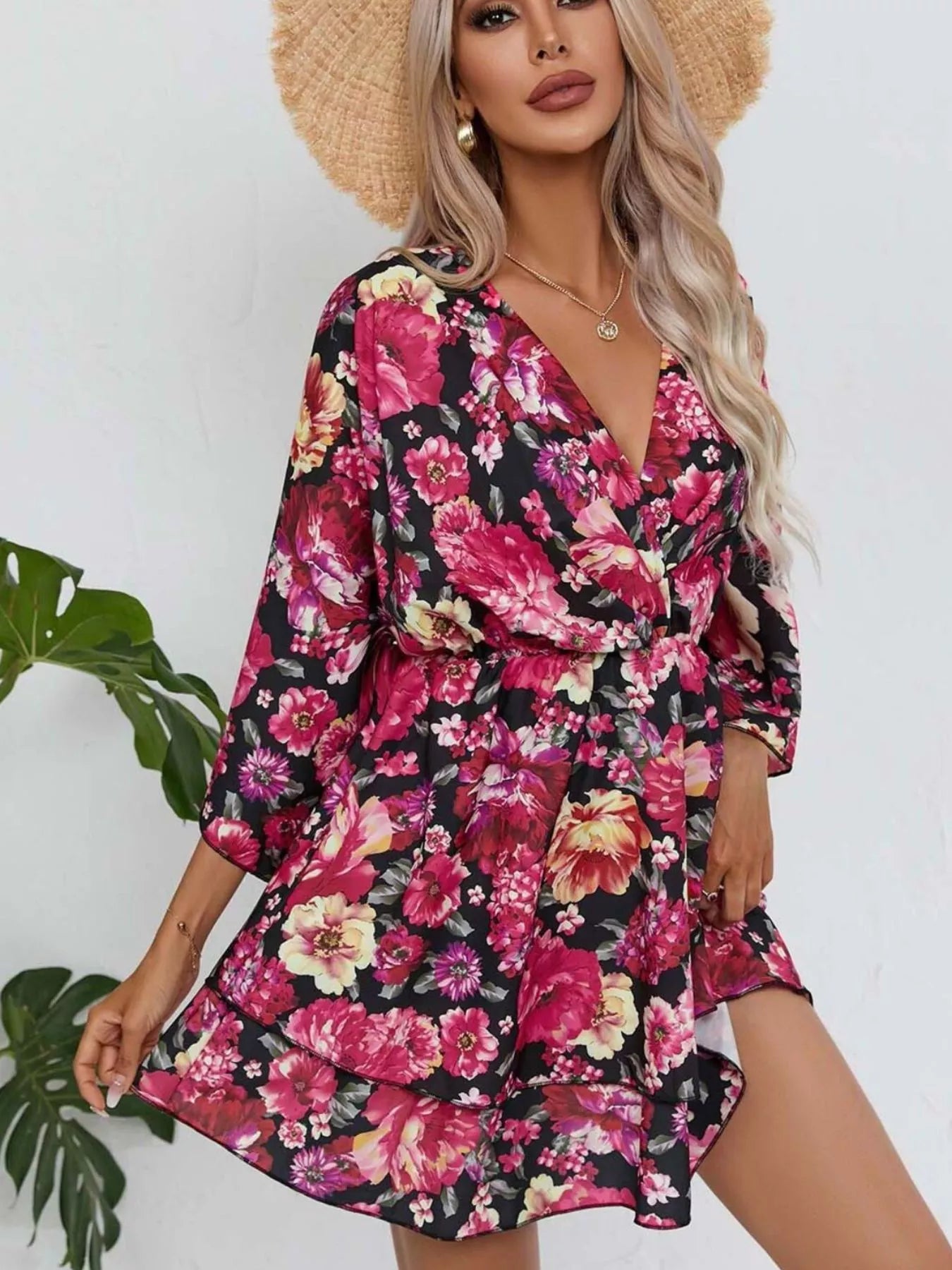 Floral mini dress with a surplice V-neckline, flowy sleeves, tiered skirt, and bright pink floral print.