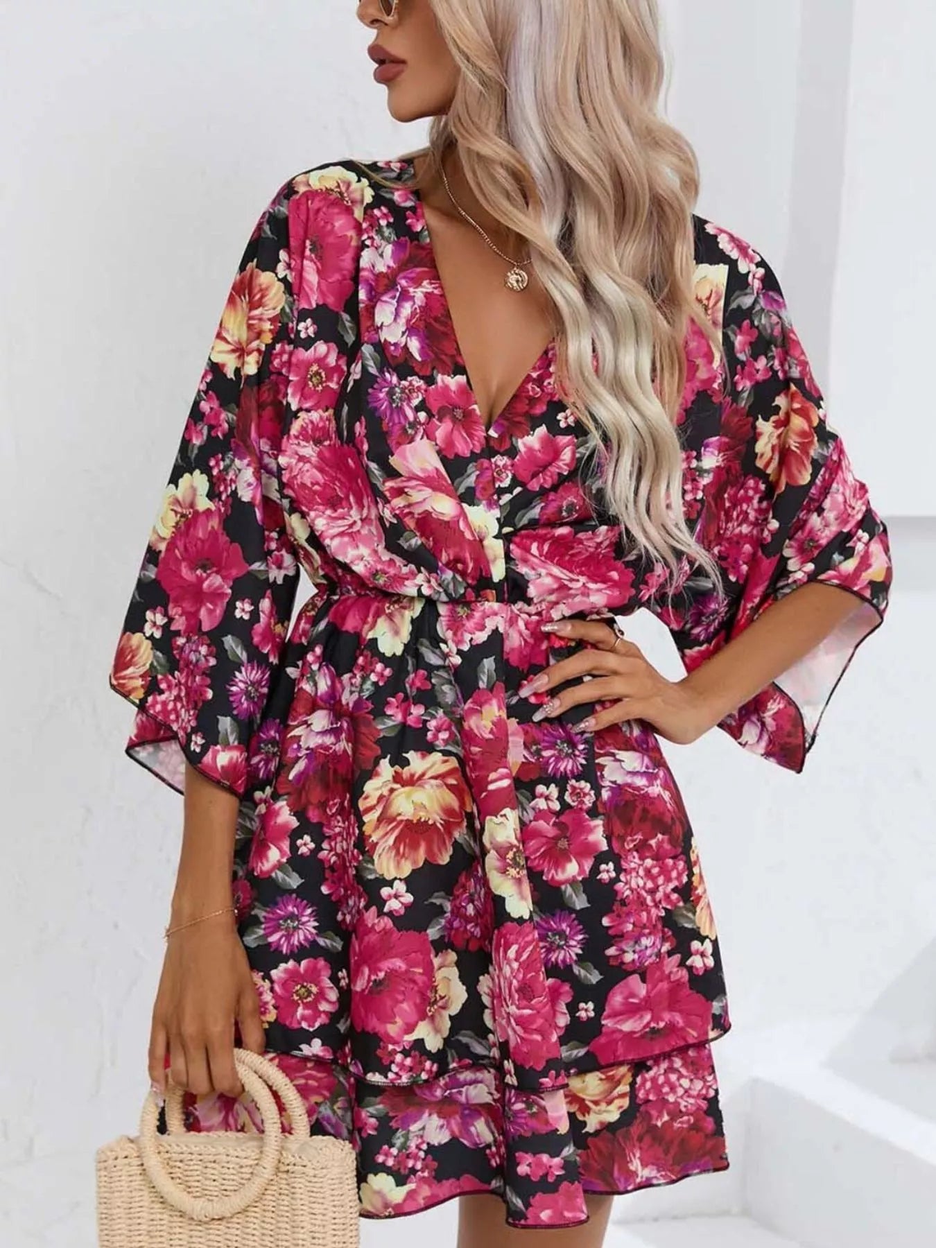 Floral mini dress with a surplice V-neckline, flowy sleeves, tiered skirt, and bright pink floral print.