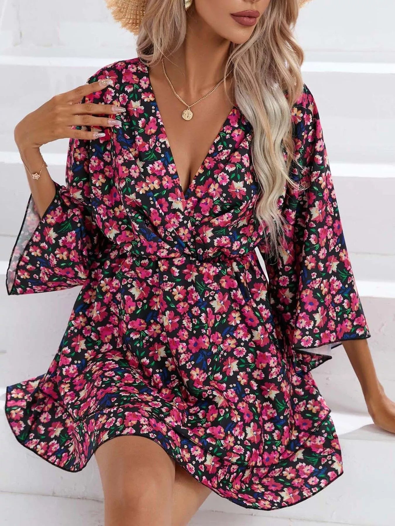 Floral mini dress with a surplice V-neckline, flowy sleeves, tiered skirt, and bright pink floral print.